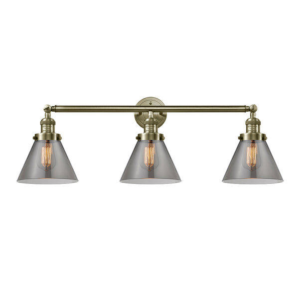 Cone Bath Vanity Light shown in the Antique Brass finish with a Plated Smoke shade