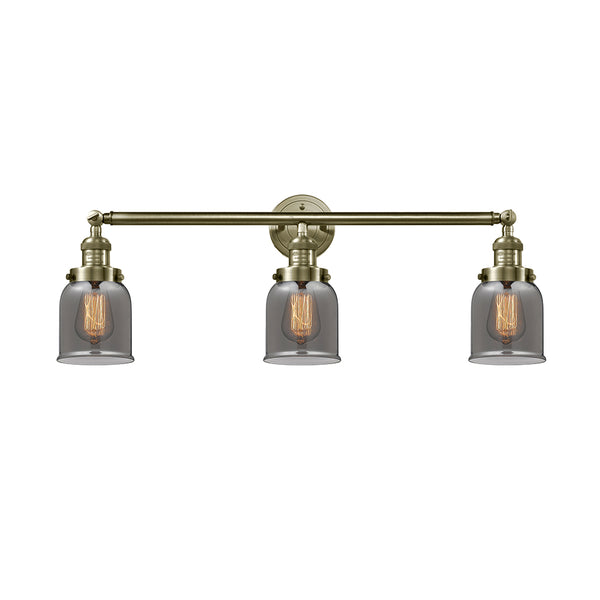 Bell Bath Vanity Light shown in the Antique Brass finish with a Plated Smoke shade