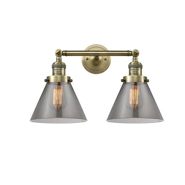 Cone Bath Vanity Light shown in the Antique Brass finish with a Plated Smoke shade