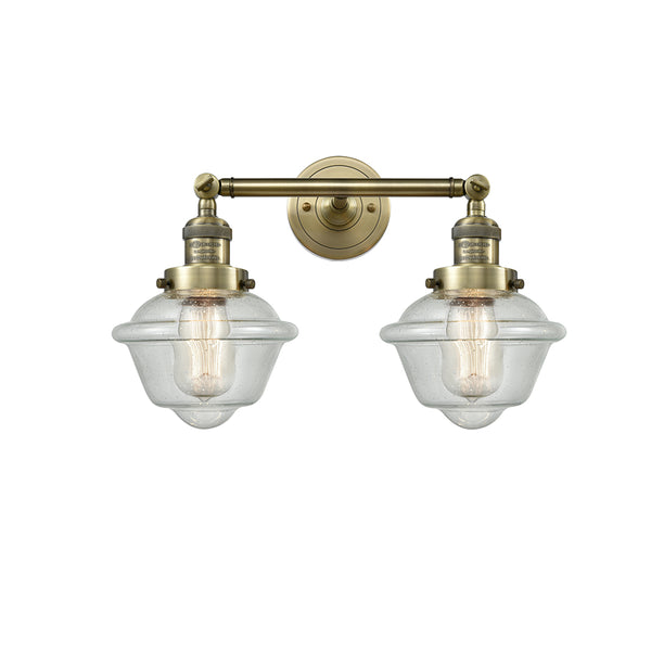 Oxford Bath Vanity Light shown in the Antique Brass finish with a Seedy shade