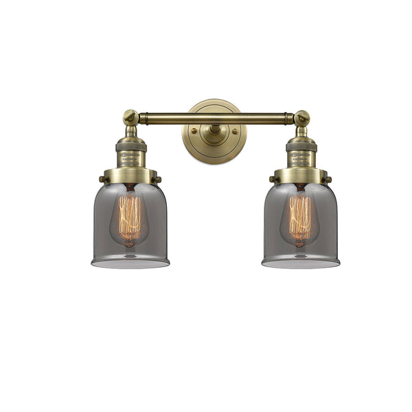 Bell Bath Vanity Light shown in the Antique Brass finish with a Plated Smoke shade