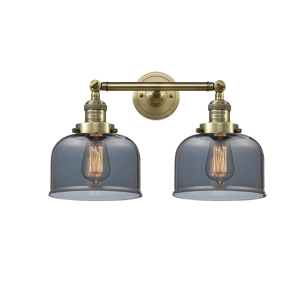 Bell Bath Vanity Light shown in the Antique Brass finish with a Plated Smoke shade