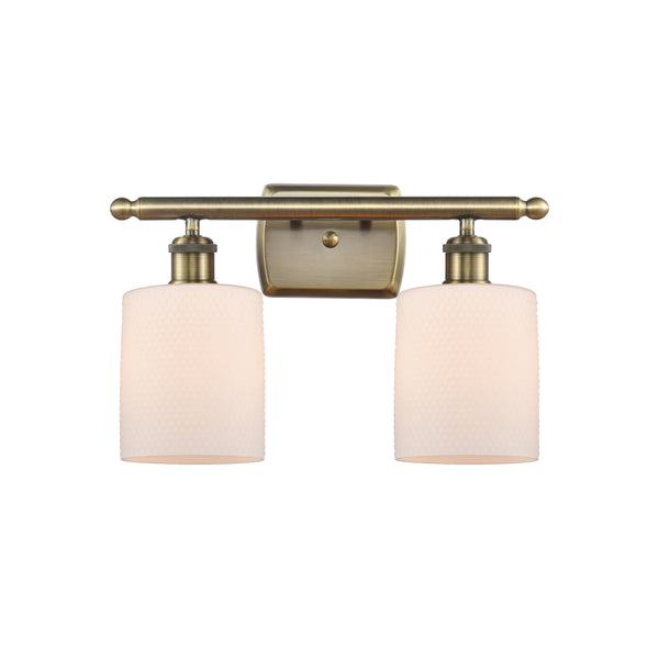 Cobbleskill Bath Vanity Light shown in the Antique Brass finish with a Matte White shade