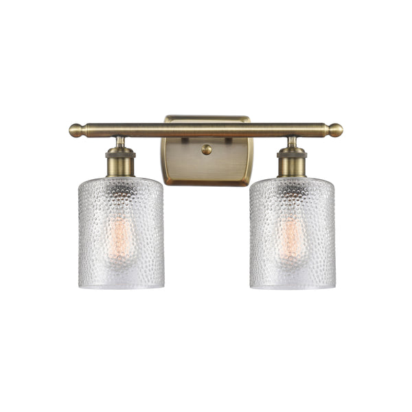 Cobbleskill Bath Vanity Light shown in the Antique Brass finish with a Clear shade