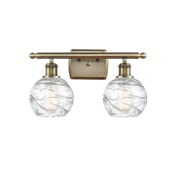 Deco Swirl Bath Vanity Light shown in the Antique Brass finish with a Clear shade