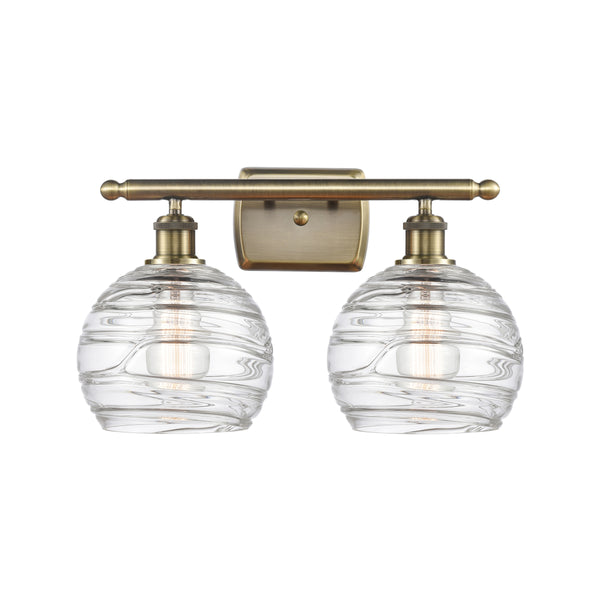 Deco Swirl Bath Vanity Light shown in the Antique Brass finish with a Clear shade