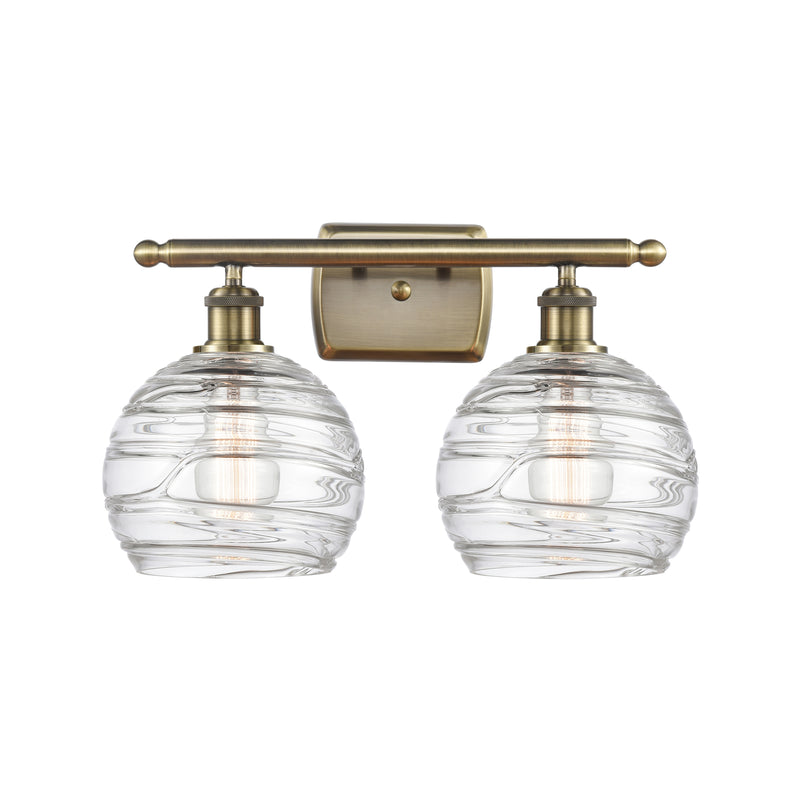 Deco Swirl Bath Vanity Light shown in the Antique Brass finish with a Clear shade