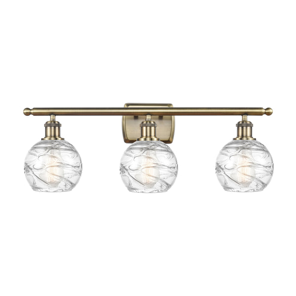 Deco Swirl Bath Vanity Light shown in the Antique Brass finish with a Clear shade