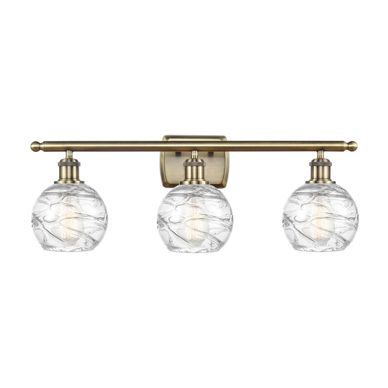 Deco Swirl Bath Vanity Light shown in the Antique Brass finish with a Clear shade